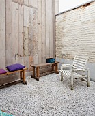 Innenhof mit Kiesboden, ausklappbarem Holztisch in Wandverkleidung sowie Holzbänken und Holzstuhl