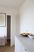 Weisses Sideboard mit Obstschale und geöffneter Zimmertür