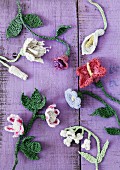 Crocheted flowers on purple wooden surface