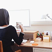 Woman sitting in front of computer monitor with mug of coffee