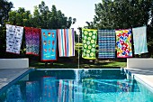 Colourful patterned towels on washing line on edge of pool in garden