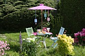 Garden table and chairs below Oriental parasol with party decorations