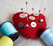 Heart-shaped pin cushion, buttons and thread