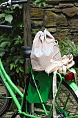 Hand-sewn, polka dot sports bag and ballet shoes on luggage rack of green-painted bicycle in garden