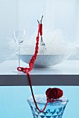 Oriental place setting: forks in bowl of glass noodles bound with red woollen yarn