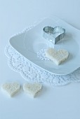 Heart-shaped slice of bread and pastry cutter on doily on white place setting