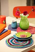 Farbenfrohe Tischdekoration mit Tellern und Vase auf Filzdeckchen