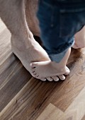 Child's feet on father's feet on walnut floor