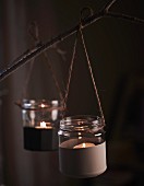 Tealight holders made from small, half-painted jam jars tied to branch with string