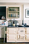 Kettle on vintage-style AGA cooker and plate rack on wall in renovated industrial building