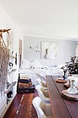 Rustic wooden table, white upholstered chair, sleeping area and natural finds on wall