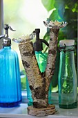 Glass candle holders on forked birch branch, vintage bottles and soda siphons