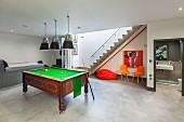 Pool room with antique pool table, trendy seating area, staircase leading upwards and view into modern wet room