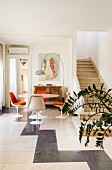 Arc lamp above tulip dining set with orange chair cushions next to masonry staircase