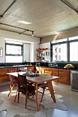 50s-style table and various chairs on animal-skin rug in simple kitchen with corner counter below windows