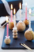 Lit candles in candlesticks made from wooden balls on slate slab