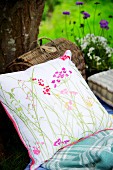 Floral cushion and picnic basket against tree trunk
