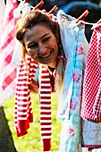 Smiling woman looking through laundry hanging on washing line in garden