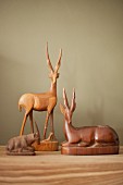 Wooden antelope figurines on wooden surface against wall painted pale grey