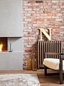 Partially visible armchair next to vintage radiator and open concrete fireplace set in brick wall