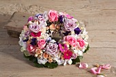 Wreath of flowers of various colours on wooden surface