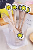 Wooden forks with whimsical smiley face stickers on bottle tops arranged decoratively for party buffet