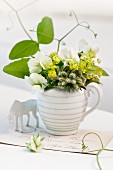 Small posy of lady's mantle, borage and sugar snap pea flowers in milk jug