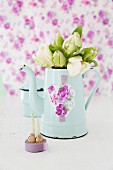 Bouquet of white tulips in nostalgic, pale blue coffee pot arranged against lilac background