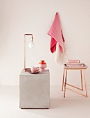 Purist lamp made from angled copper pipes and copper stool; crockery and fabrics in shades of pink