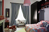 Aeroplane pedal car in faux-antique boy's bedroom; double bed with patchwork covers and headboard integrated into dark blue fitted wardrobe