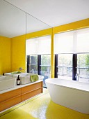 Renovated bathroom with sun-yellow mosaic tiles and washstand with countertop basin on mirrored wall