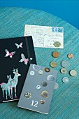 Nostalgically decorated note books, coin collection and old postcard on turquoise surface