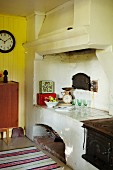 Chimney above old, rustic fireplace and clock on yellow wooden wall in background