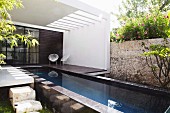 Pool and shell chairs with cord seats on roofed terrace of Mexican house with long, narrow pool