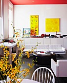 Loungebereich mit rundem Couchtisch und weißem Sofa vor Wand mit gelben Bildern über Sideboard