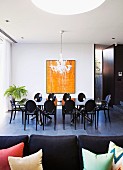 View of long dining table and black chairs with oval backrests in modern setting