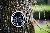 Message on sign hanging on tree trunk