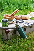 Picnic equipment, bread and salad on top of vintage suitcase