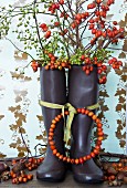 Wreath of rose hips tied to wellington boots filled with branches of rose hips