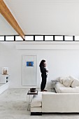 Mother and baby in minimalist living room with white sofa, pale stone floor and high ribbon window with black metal frame