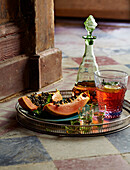 Metal tray with papaya, glass carafe and drink