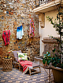 Lounger with colorful items of clothing above it in the courtyard with natural stone wall and tiled floor