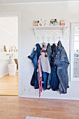 Jeans hanging from clothes rack below ornaments on shelf flanked by open door and picture frame