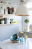 Retro lamp above crockery and yellow carnations in glass vases on white dining table