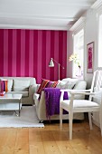 Seating area in Scandinavian living room with white furniture against red and pink striped wallpaper