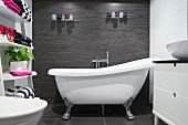 Free-standing, clawfoot bathtub in bathroom with white and charcoal tiles and towels on ladder shelves to one side