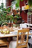 Basket of apples on wooden table and old kitchen chairs in front of wooden cabin