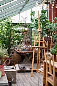 Easel in front of potted plants and gardening utensils in greenhouse