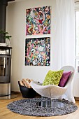 Scatter cushions on swivel easy chair on round long-pile rug in front of comic-style artworks on wall