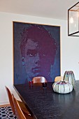 View across dining table to large, modern portrait on wall